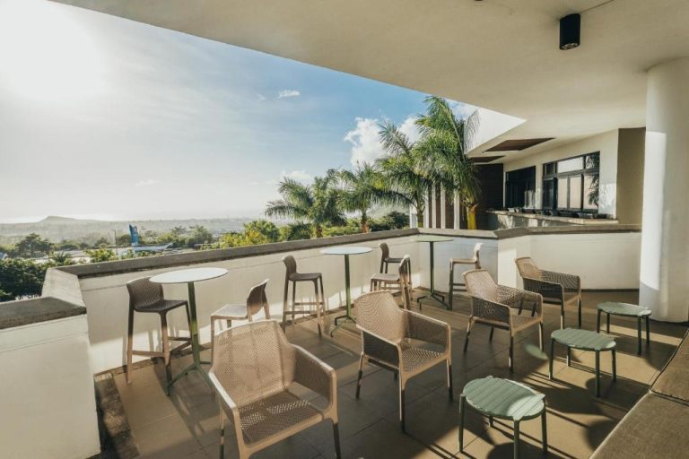 Terraza exterior con sillas y mesas del hotel Voila Bagatelle con vistas panorámicas y palmeras