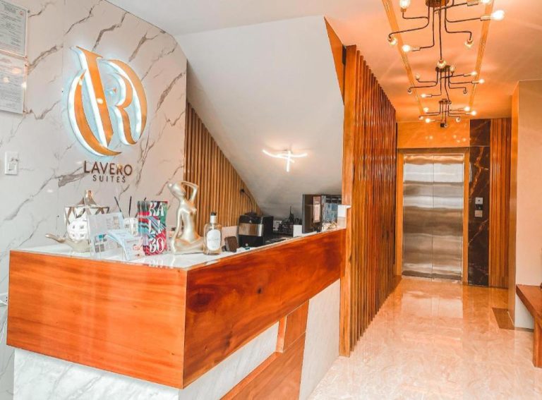 Recepción moderna con mostrador de madera y mármol en Lavero Suites con iluminación elegante