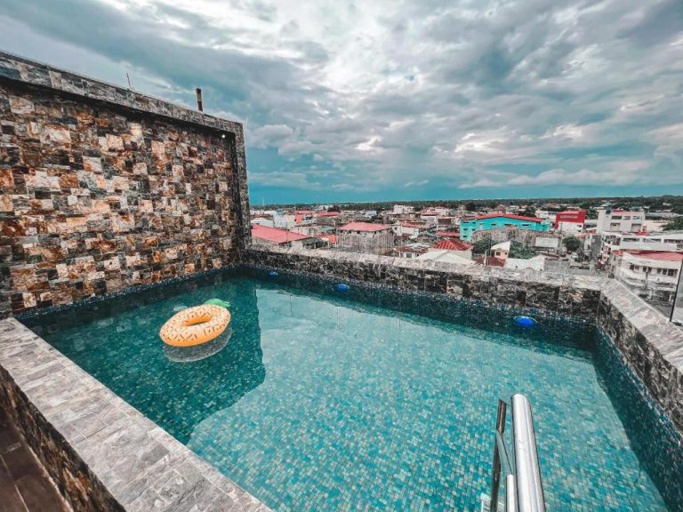 Piscina rooftop con flotador de piña y vistas panorámicas de la ciudad en Lavero Suites