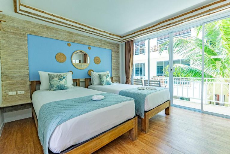 Habitación doble con decoración marinera azul y balcón con vistas tropicales en ARKbar Beach Club Resort