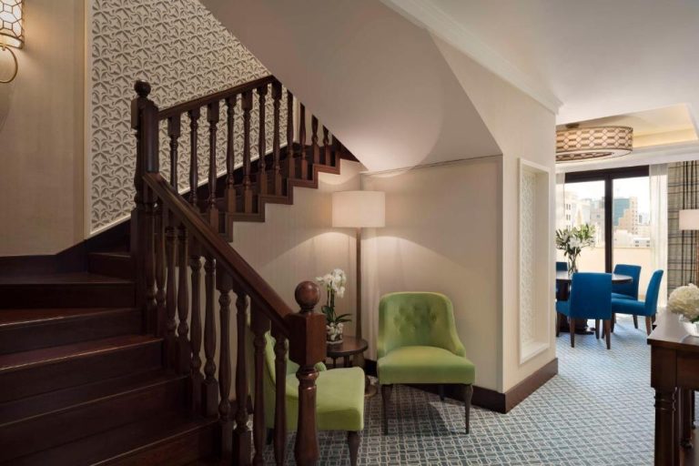 Suite dúplex con escalera de madera y salón comedor del Al Najada Doha Hotel by Tivoli