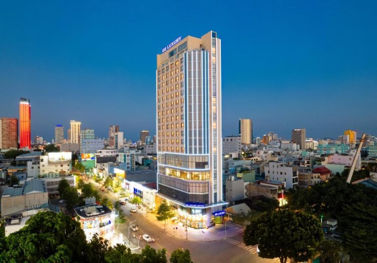 Vista nocturna de la fachada iluminada del G8 Luxury Hotel Da Nang con el skyline de la ciudad
