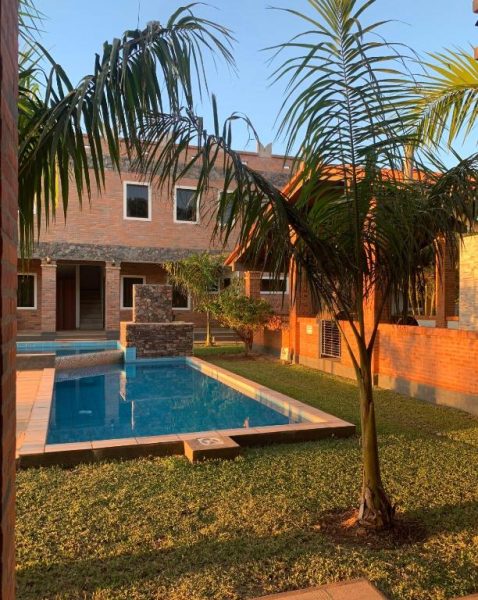 Piscina exterior rodeada de palmeras y jardín del Hotel Il Castello con fachada de ladrillo
