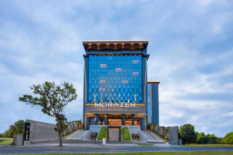 Fachada exterior del hotel Morazen Yogyakarta con imponente edificio de cristal azul y entrada principal