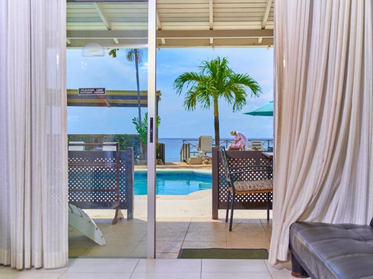 Piscina exterior con vistas al mar y palmeras del Tropical Sunset Beach Apartment Hotel