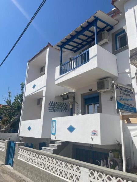 Fachada exterior blanca con balcones azules de Pansion Katerina, alojamiento con habitaciones en alquiler en Grecia