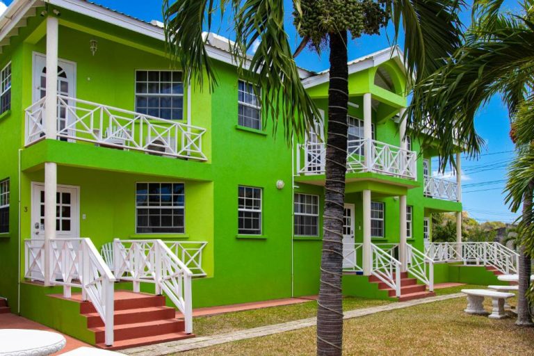 Fachada exterior verde con balcones blancos y palmeras del Best E Villas Prospect St James en Barbados