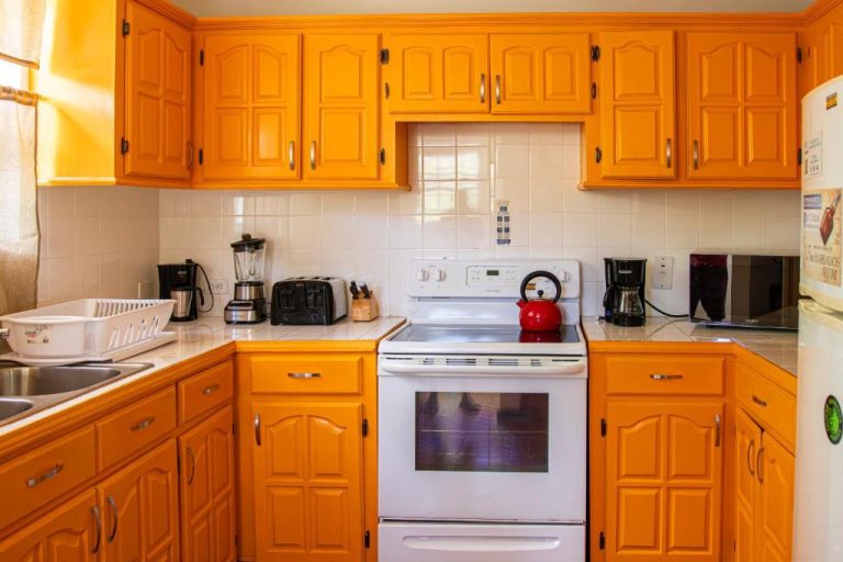 Cocina completamente equipada con armarios naranjas y electrodomésticos en Best E Villas Prospect St James