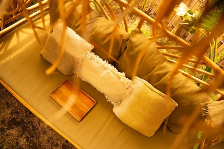 Sofá de bambú con cojines naturales y bandeja de madera en zona exterior del hotel Selvática