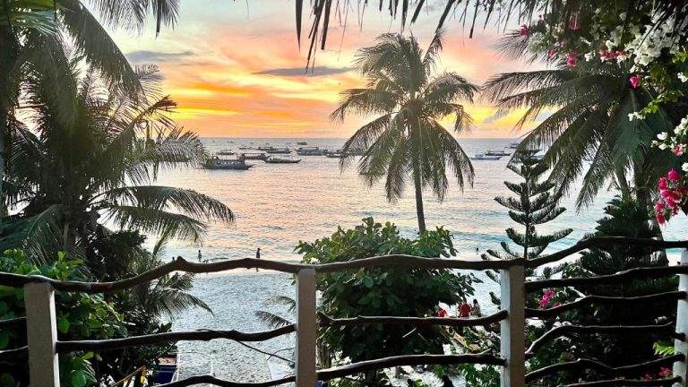 Vista al atardecer desde la terraza del Kaiyana Boracay Beach Resort con palmeras y barcos en el mar