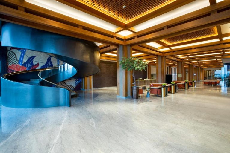 Lobby del Hotel Morazen Yogyakarta con espectacular escalera espiral azul y techo de madera iluminado