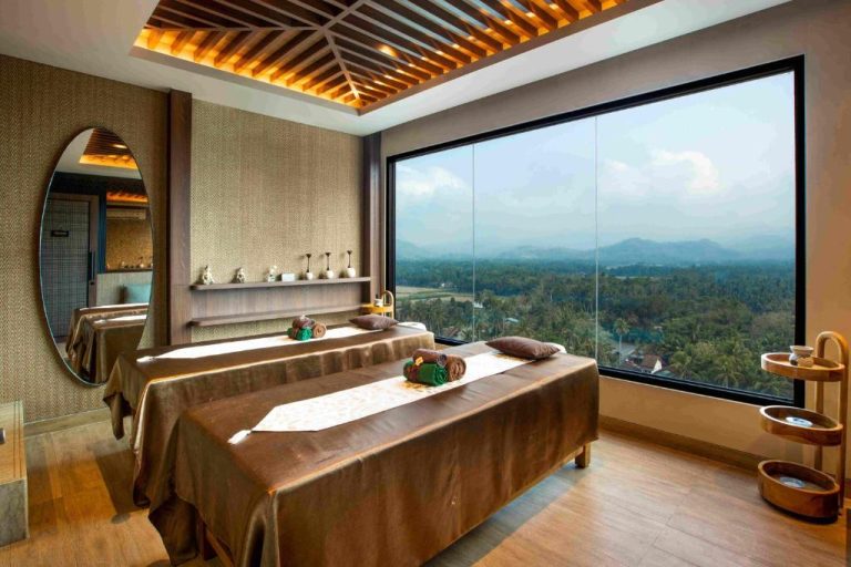 Sala de masajes con dos camillas y vista panorámica a la selva y montañas en MORAZEN Yogyakarta