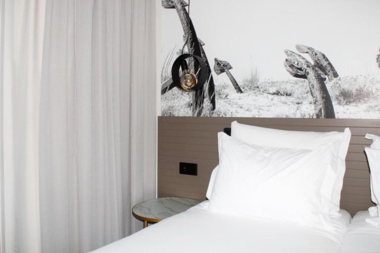 Habitación doble con cama blanca y mural fotográfico en blanco y negro en AP Cabanas Beach & Nature
