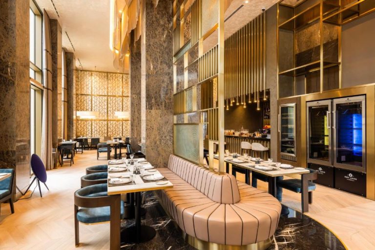 Elegante restaurante interior del Merit Starlit Hotel con mobiliario de lujo, mármol y vitrinas de maduración de carnes