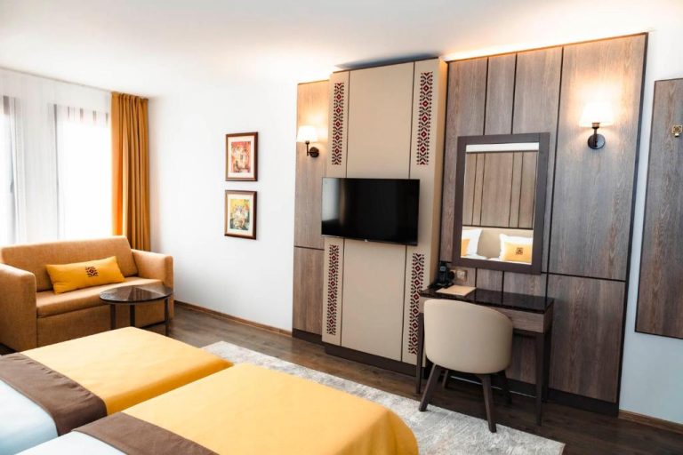 Habitación doble con escritorio, televisión y decoración en tonos dorados del Spa Complex Aleksandar