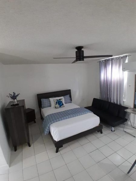Habitación doble con cama matrimonial, sofá y ventilador de techo en Beach Studio 21