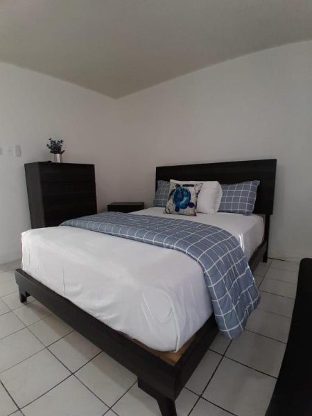 Habitación con cama doble y ropa de cama azul cuadriculada en Beach Studio 21