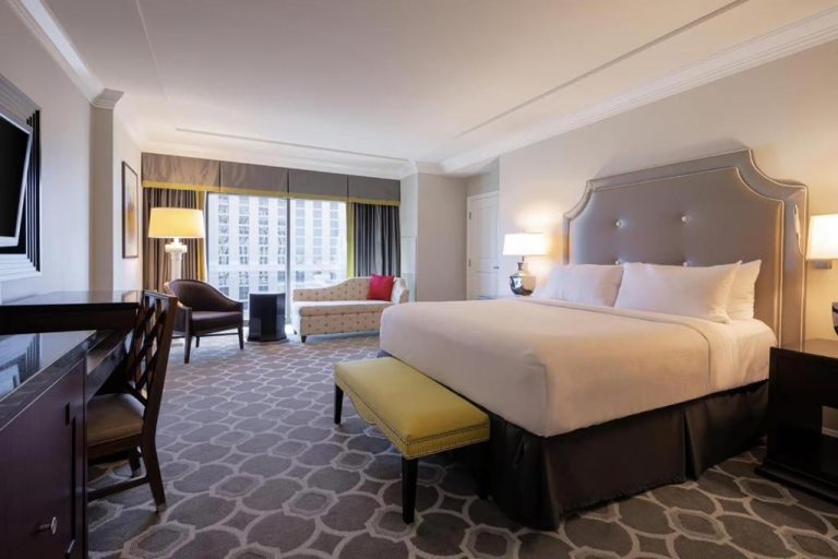 Habitación king deluxe con cama doble y banco amarillo en Caesars Palace Las Vegas by Suiteness