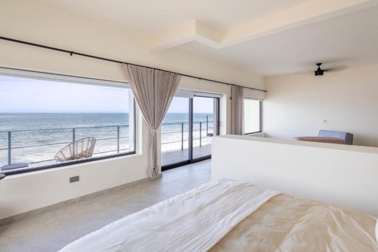 Habitación luminosa con cama y ventanal panorámico con vistas al mar en Cabo Break Hotel