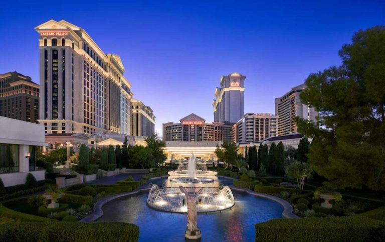 Fuente iluminada y jardines exteriores del Caesars Palace Las Vegas al atardecer con vistas a las torres del hotel