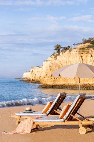 Tumbonas con sombrilla en la playa privada del Vilalara Grand Hotel Algarve con acantilados al fondo