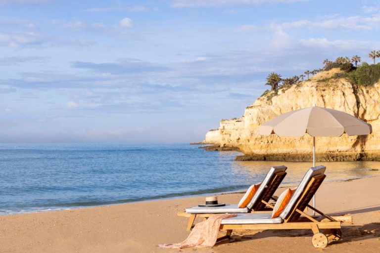 Tumbonas con sombrilla en la playa privada del Vilalara Grand Hotel Algarve con acantilados al fondo