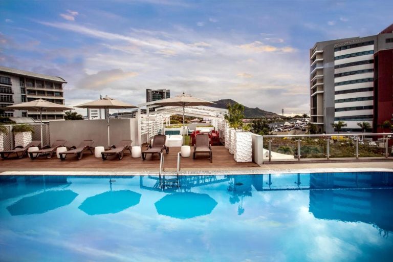 Piscina exterior con tumbonas y sombrillas en la terraza del Hennessy Park Hotel Mauricio