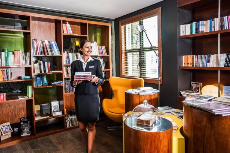 Recepcionista del Hennessy Park Hotel sosteniendo libros en la elegante biblioteca del hotel