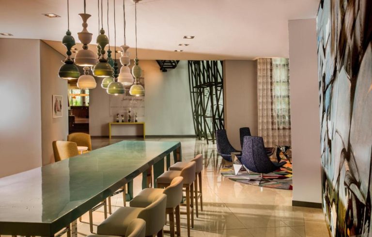 Elegante lobby del Hennessy Park Hotel con mesa verde, lámparas decorativas y zona lounge de diseño contemporáneo