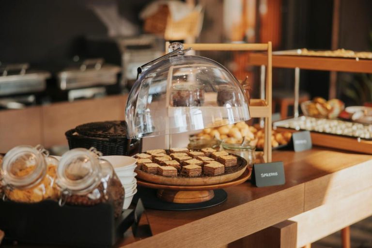 Buffet de desayuno con repostería y bollería variada bajo campana de cristal en Infinity Hotel & More