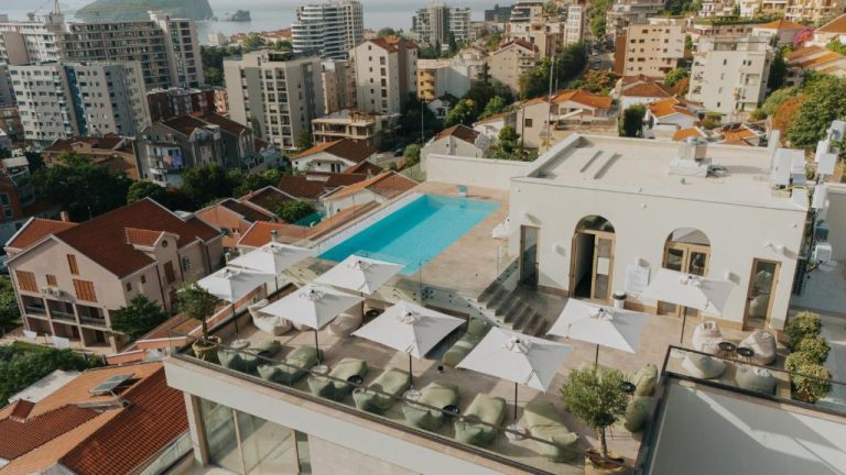 Terraza rooftop con piscina exterior y tumbonas del Infinity Hotel & More con vistas a la ciudad