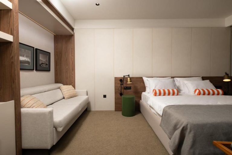 Habitación doble con cama king size y sofá en Infinity Hotel & More, decoración moderna en tonos neutros