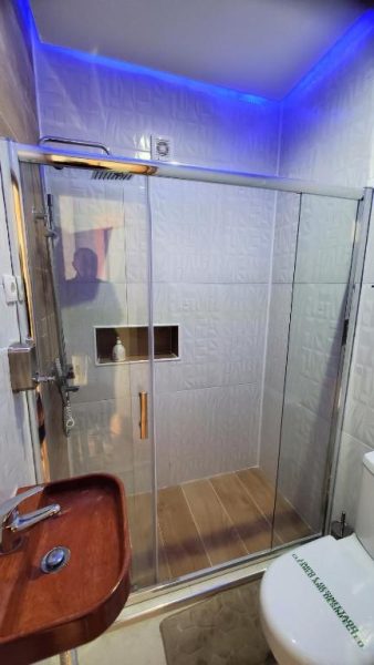 Baño moderno con ducha de cristal e iluminación LED azul en Fajã Beach House