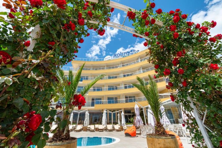 Piscina exterior con arco de rosas rojas y tumbonas del Aphrodite Beach Hotel