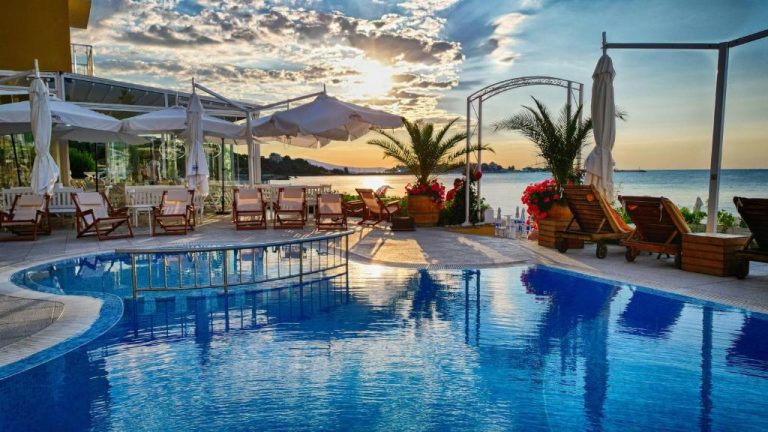 Piscina exterior del Aphrodite Beach Hotel con vistas al mar y tumbonas al atardecer