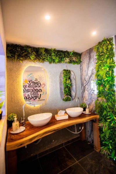 Baño decorado con plantas naturales y lavabos de diseño en madera del Hotel Marie Real Cartagena