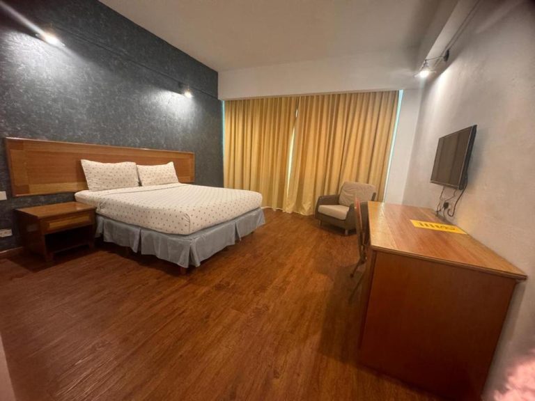 Habitación doble con cama matrimonial, tarima de madera y televisor en Mayres Hotel