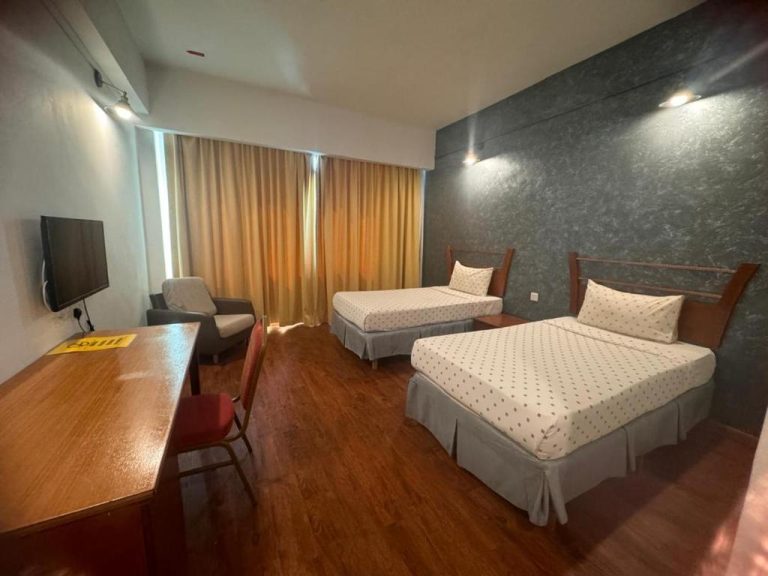Habitación twin con dos camas individuales, escritorio de madera y pared de piedra en Mayres Hotel