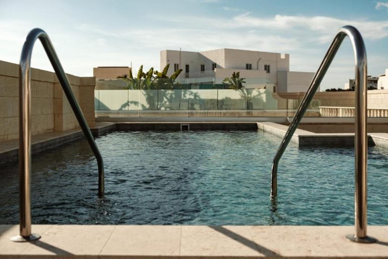 Piscina exterior con barandillas de acero del Palazzo Castagna Boutique Hotel y vistas a edificios