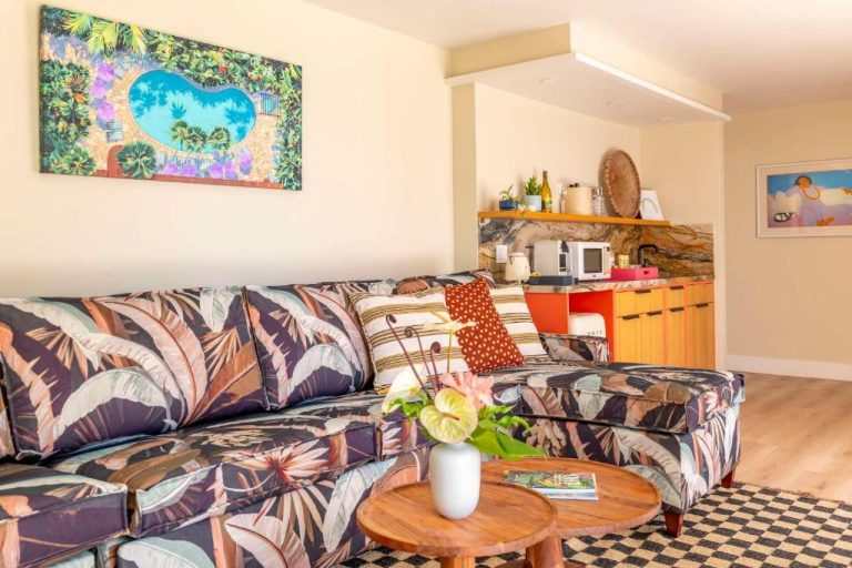 Sala de estar tropical con sofá estampado y cocina americana en Wayfinder Waikiki Hawaii