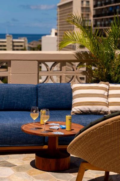 Terraza lounge con sofá azul y vistas al océano en el hotel Wayfinder Waikiki, Hawaii