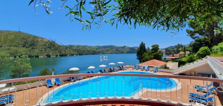 Piscina exterior con tumbonas y vistas al lago en el Lago Azul Eco Hotel rodeado de montañas