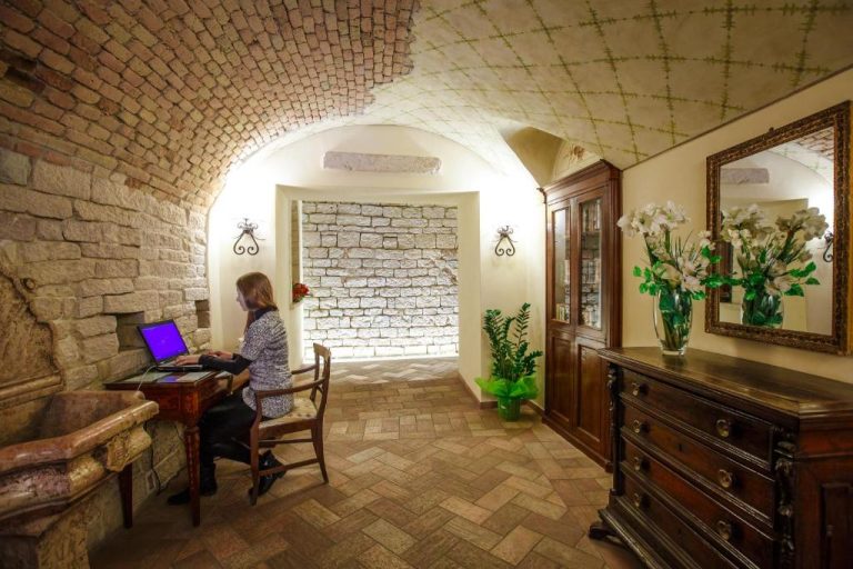 Lobby con bóveda de piedra y zona de trabajo del Hotel Fortuna con decoración rústica medieval