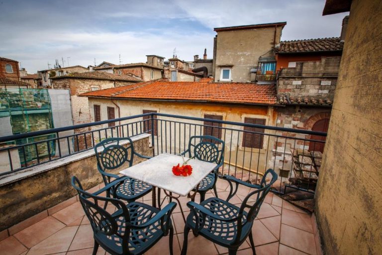Terraza exterior con mesa y sillas del Hotel Fortuna con vistas a los tejados históricos de la ciudad