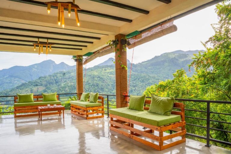 Terraza con sofás de palets y cojines verdes en Eco Vibe Resort con vistas panorámicas a las montañas