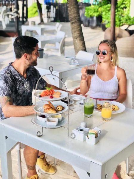 Pareja disfrutando de un desayuno en terraza frente al mar en El Taj Oceanfront and Beachside Condo Hotel