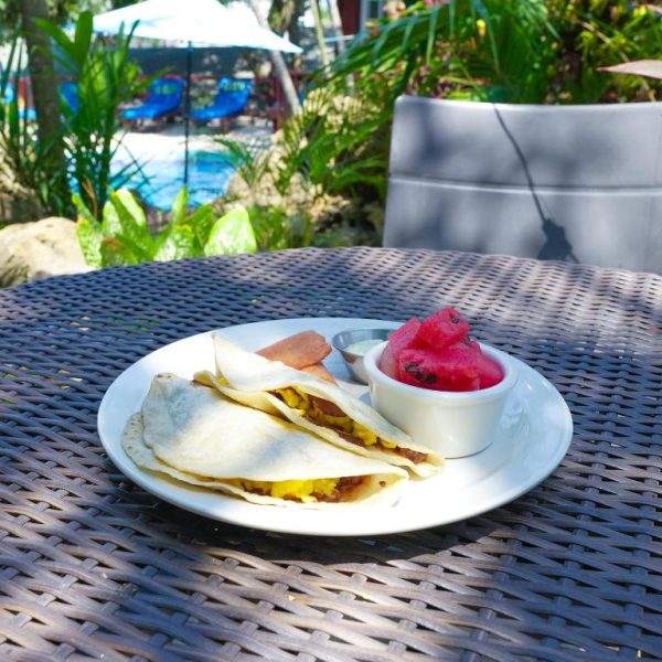 Desayuno con tacos de huevo y fruta tropical en la terraza junto a la piscina del West Bay Lodge and Spa