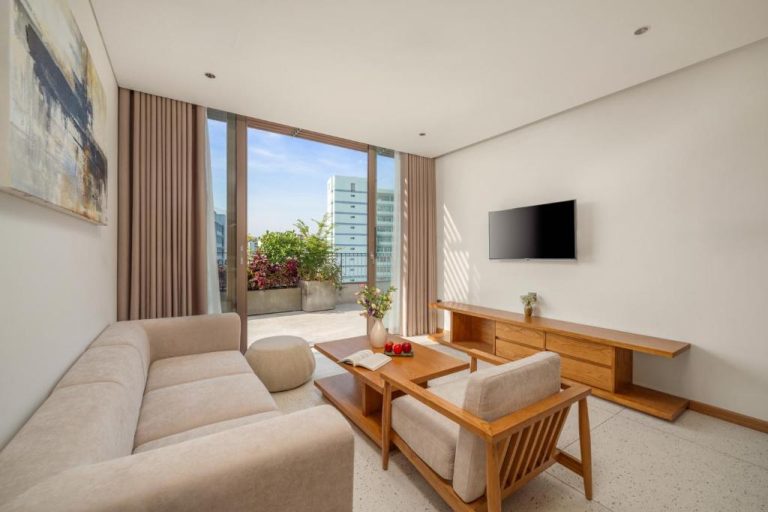 Salón moderno con sofá, TV y terraza exterior en Vernal Hotel & Apartment Da Nang