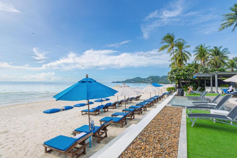 Tumbonas azules y sombrillas en la playa privada del KC Beach Hotel Samui en Tailandia
