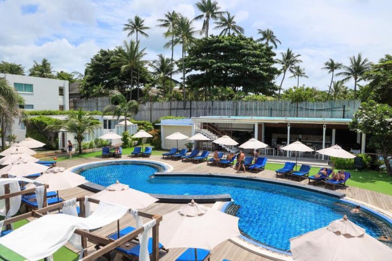 Piscina exterior con tumbonas azules y sombrillas del KC Beach Hotel Samui en Tailandia